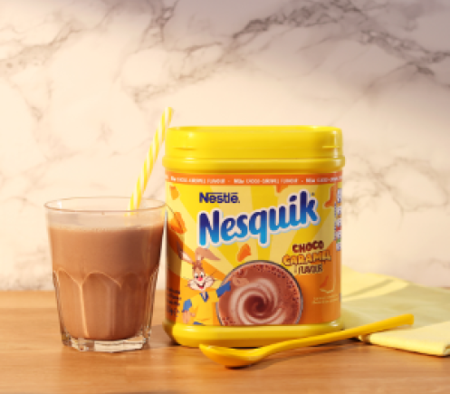 NESQUIK_40001_CHOCO_CARAMEL_SOCIAL_LAUNCH_16x9.png Nesquik Choco-Caramel Milkshake Powder 500g on Table with Glass